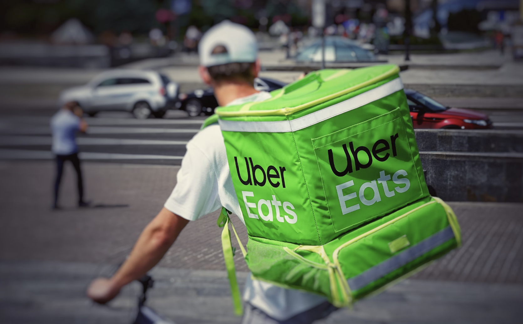 A delivery rider on a bicycle with a green Uber Eats backpack.